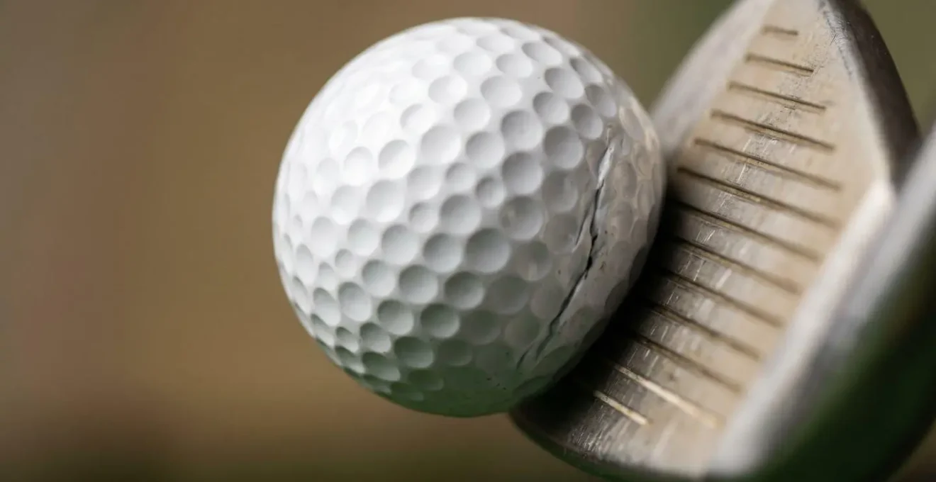 Macro close-up of golf ball at moment of impact showing compression texture and energy transfer