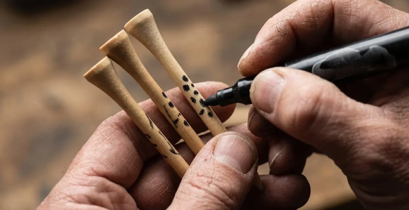 Close-up of hands marking golf tees for consistent height with measurement tools