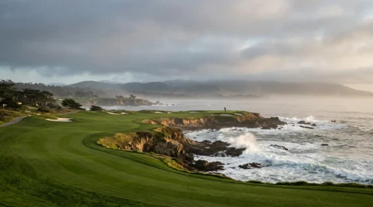 Dramatic view of Pebble Beach's iconic 18th hole at golden hour with Pacific Ocean waves